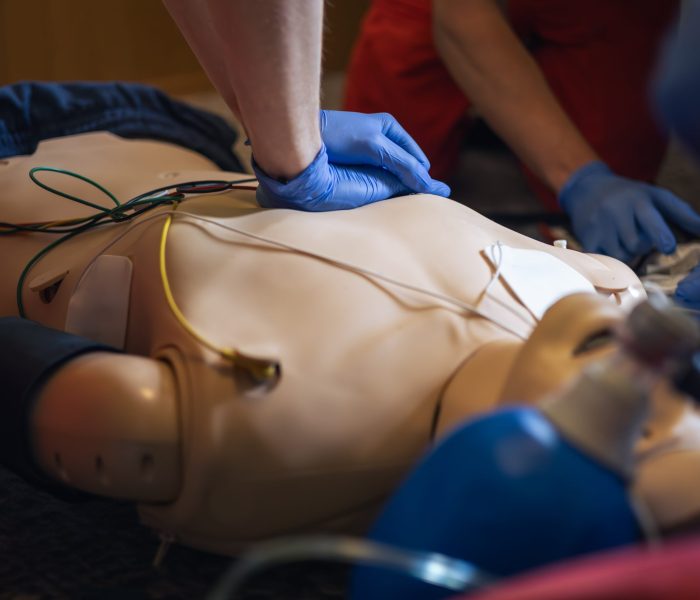 Hands of paramedic and doctor during resuscitation. Team of emergency medical service during CPR training on dummy. Themes rescue, urgency and health care.