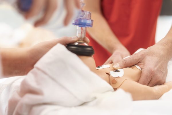 Hands of paramedic of emergency medical service during training resuscitation training on newborn dummy.